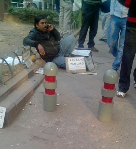 पैन कार्ड बनाने की फुटपाथिया दुकान चलाता विकलांग व्यक्ति।