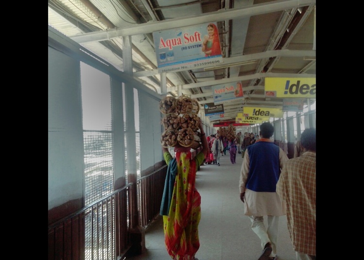 सिर पर लकड़ी का गठ्ठर ले कर जाती इलाहाबाद स्टेशन के फुट ओवर ब्रिज पर महिला। 