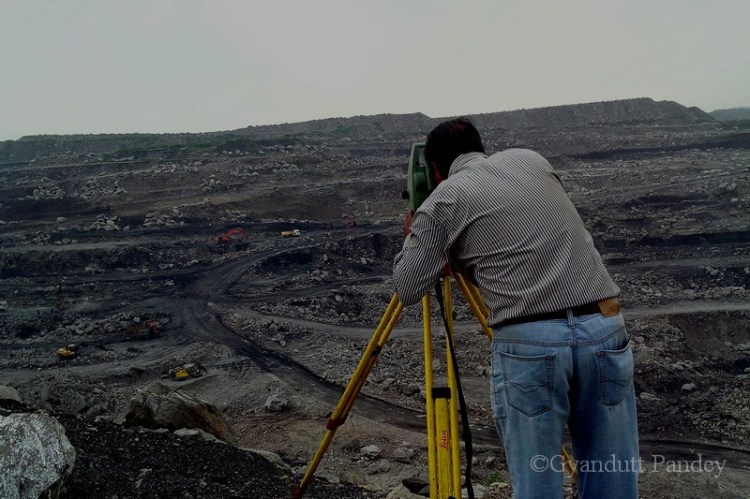एक व्यक्ति कोयला खनन/वहन का असेसमेण्ट के लिये एक ट्राइपॉड पर दूरबीन लगाये हुये थे। नीचे अपने सहकर्मी से वे मोबाइल के माध्यम से बात कर रहे थे।